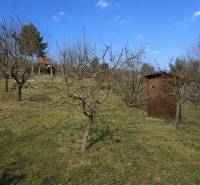 Gardens at Opendáky in Osuské with grass, trees, and a wooden shelter.