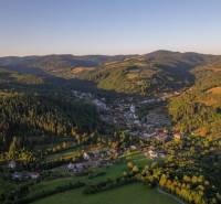 A mountainous landscape with agricultural and forest lands in the village of Lazy pod Makytou at sunset.