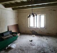 An abandoned room with cracked walls and a broken window in a family house.