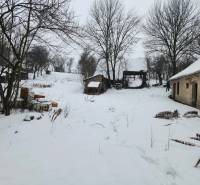 A snowy yard of a family house in Felsőtelekes with visible wooden structures.