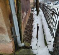 A snowy exterior of a family house in Felsőtelekes, next to the gutter pipe and fence.