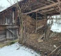 A wooden structure at a family house in Felsőtelekes, covered with snow and trees.