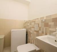 Bathroom with a washing machine, sink, and laundry basket in a 2-room apartment.