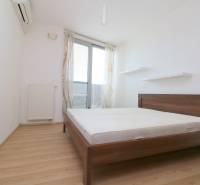 A bedroom with a bed, shelves, and a wooden decor floor in a two-room apartment.