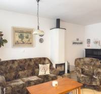 Living room in a family house with a sofa, fireplace, piano, and wall decorations.