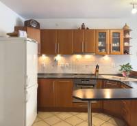 A kitchen in a family house with wooden cabinets and a white refrigerator.