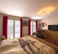 A bedroom in a family house with access to a balcony, red curtains, and a comfortable armchair.