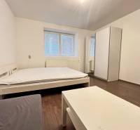 White bed, wardrobe, table, and floor with wood decor in a studio apartment.