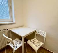 A small dining nook with a white table and two chairs in a studio apartment.