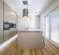 A kitchen in a family house with an island, built-in appliances, and a wooden decor floor.