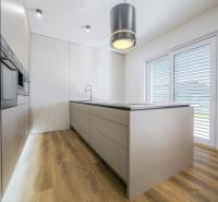 A kitchen in a family house with a wood-patterned floor and built-in appliances.