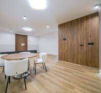 Dining table with white chairs and a wall with wooden decor in a family house.