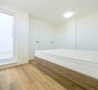 A bright bedroom with a bed and wood-decorated flooring in a family house.