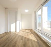 A room in a family house with a wooden decor floor and large windows.