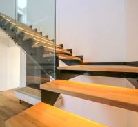 Modern staircase with wooden decor and glass railing in a family house.