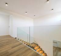A family house with a staircase and a wooden decor floor, ceiling lights.