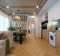 Interior of a 3-room apartment with a kitchen, dining table, and wooden decor flooring.