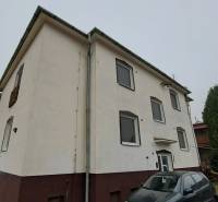 A family house in Kalná nad Hronom with parked cars and a coniferous tree in the yard.