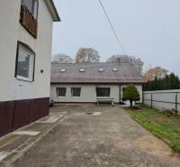 A family house in Kalná nad Hronom with a paved courtyard, greenery, and fencing.