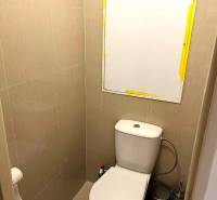 A toilet with tiled walls and a mirror in a 3-room apartment.