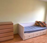 A bright room in a 3-room apartment with a bed and a dresser on a wooden-decor floor.