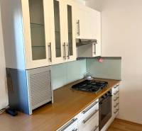 A kitchen in a 3-room apartment with a gas stove and a floor with a wooden decor.