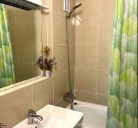 A bathroom in a 3-room apartment with a bathtub, shower, and green curtain.