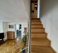 A staircase in a 3-room apartment with a wooden decor floor and a Christmas tree.