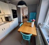 A kitchen in a 3-room apartment with a white kitchen unit, a wooden table, and a turquoise refrigerator.