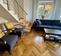 Living room in a 3-room apartment with a wooden decor floor, staircase, sofa, and armchairs.