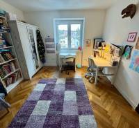 Children's room in a three-room apartment with a wooden decor floor and a desk.