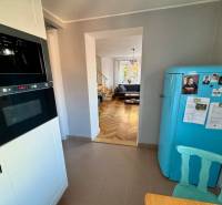 A kitchen with a retro refrigerator, a view of the living room, and a wooden decor floor in a 3-room apartment.