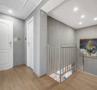 A hallway in a family house with a wooden decor floor, a painting, and a railing.