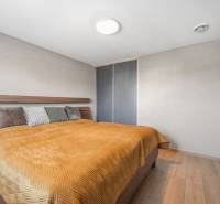 Bedroom in a family house with a bed, wardrobe, and wooden decor flooring.