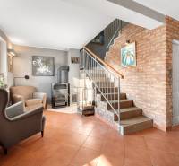 Living room in a family house with a brick wall, staircase, and fireplace.
