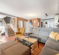 Living room with a brick wall, furniture, and a fireplace in a family house. Rustic interior with a carpet.
