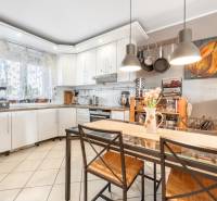 A kitchen in a family house with white cabinets, a glass table, and decorative accessories.