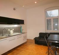 A kitchen in a 3-room apartment with a wooden decor floor and black furniture.