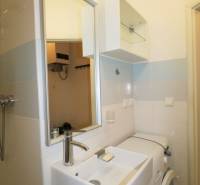 A bathroom with a sink, mirror, and washing machine, suitable for a 3-room apartment.