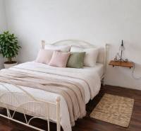 Bedroom in a family house with a bed, decorative pillows, and a wooden-patterned floor.