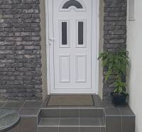 Entrance to a family house in Horné Saliby, white door, brick cladding, stairs with greenery.