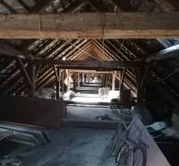 Attic of a family house with an old wooden beam roof structure, a room full of objects.