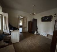 A room in a family house with a wooden decor floor, older furniture, and decorative paintings.