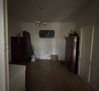 A room in a family house with wooden decor flooring, simple decorations, and furniture.