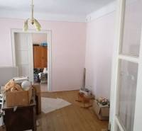 A messy room in a family house with a wooden decor floor and simple furniture.
