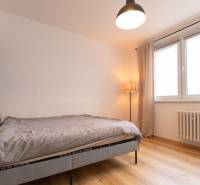 Bedroom in a 3-room apartment with a comfortable bed, wood-patterned flooring, and a large window.