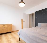 A bedroom in a 3-room apartment with a wooden decor floor, a comfortable bed, and a dresser.