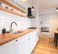 A kitchen in a 3-room apartment with white cabinets, a dining table, and a floor with a wood decor.