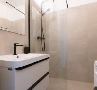 A bathroom in a 3-room apartment with a bathtub, black faucet, and washing machine.
