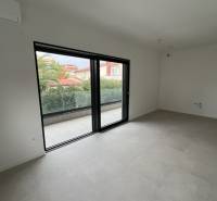 Spacious interior of a holiday apartment with a balcony, large glass doors, and tiled flooring.